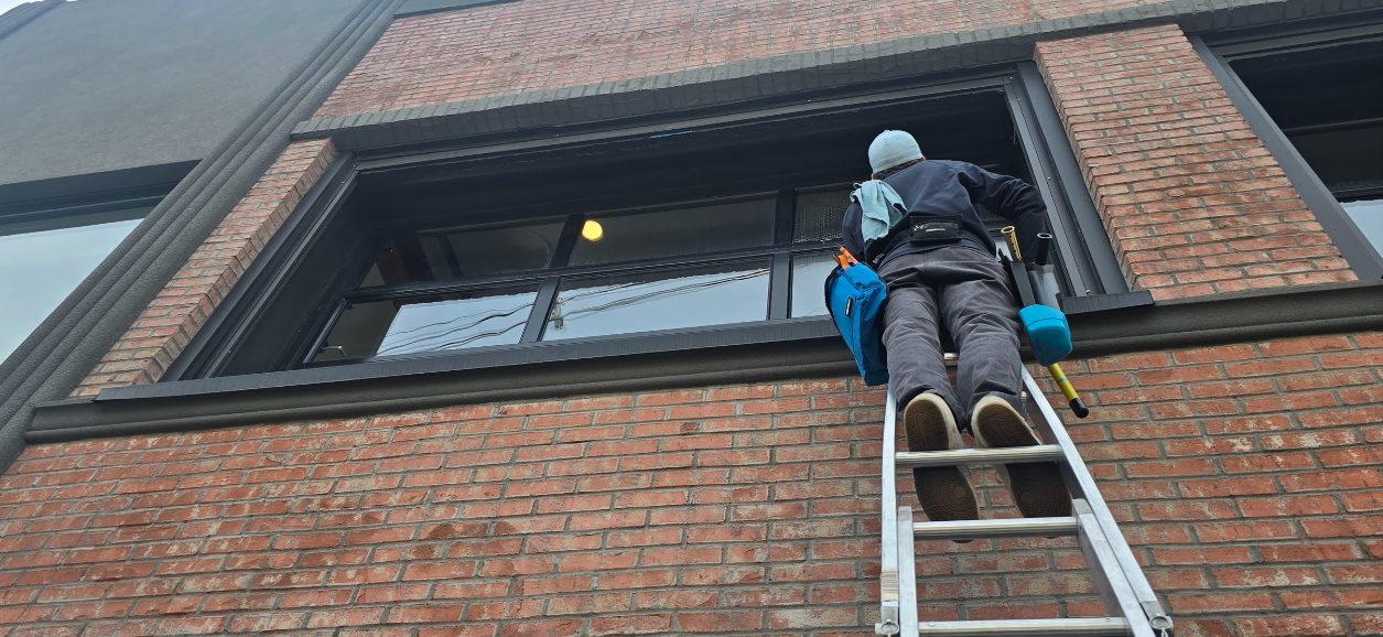 Owen Window Care cleaning second-story windows on a brick commercial building