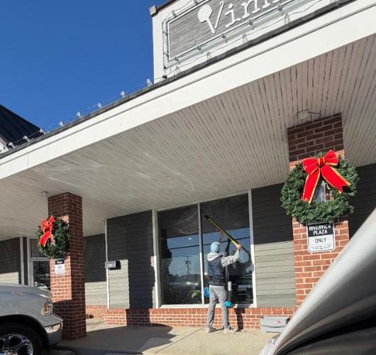 Cleaning storefront windows at a shopping plaza with a water-fed pole